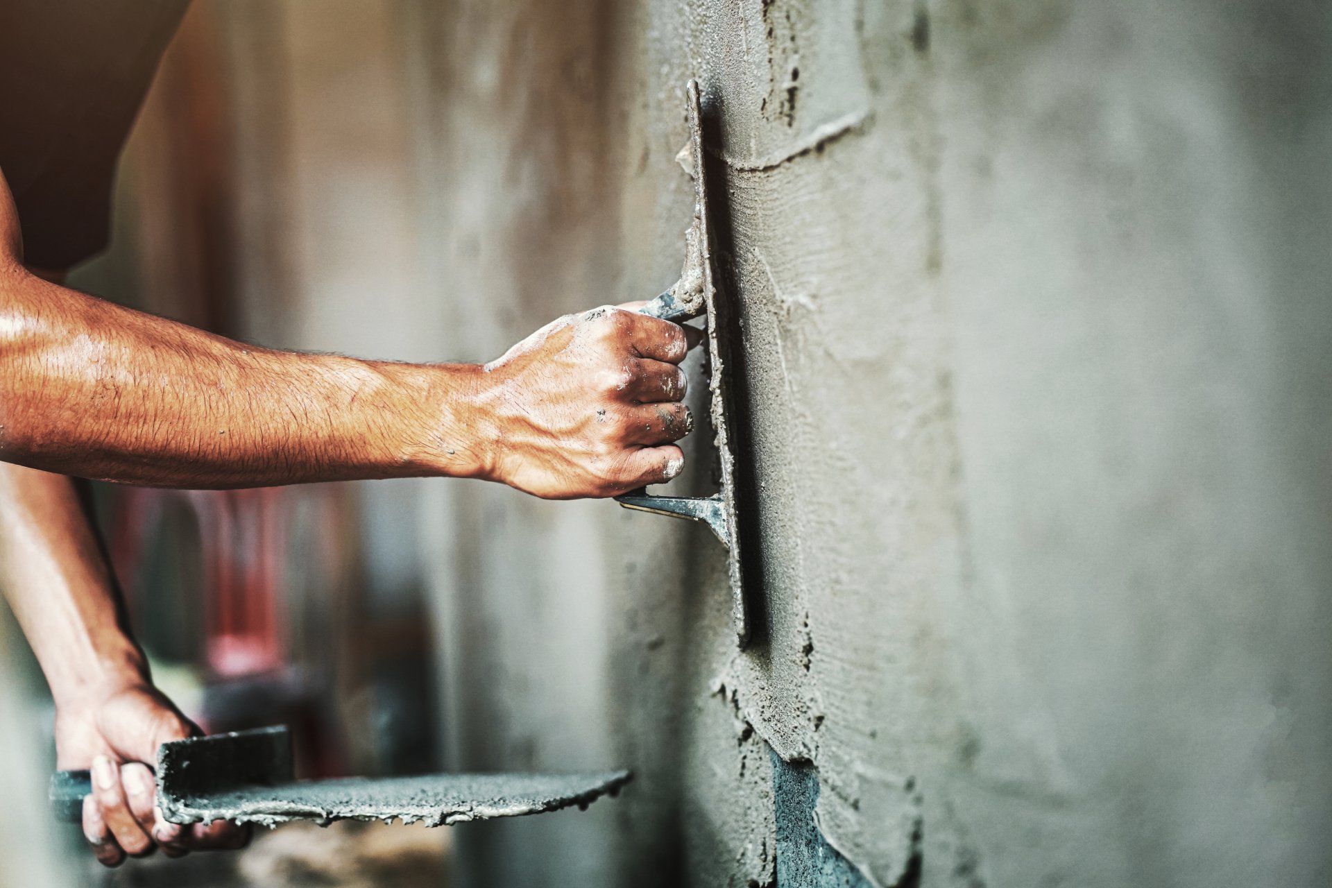 man plastering cement on wall